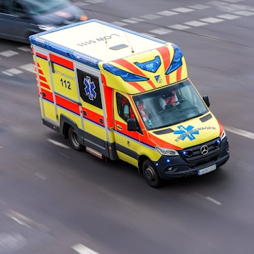 Ein Rettungswagen fährt mit Blaulicht über eine Straße.