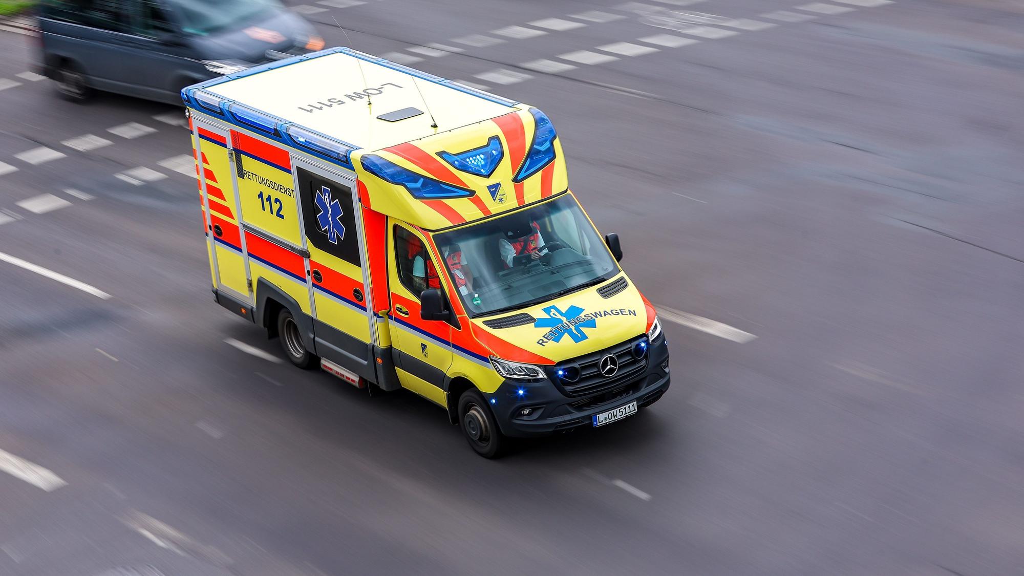 Ein Rettungswagen fährt mit Blaulicht über eine Straße.
