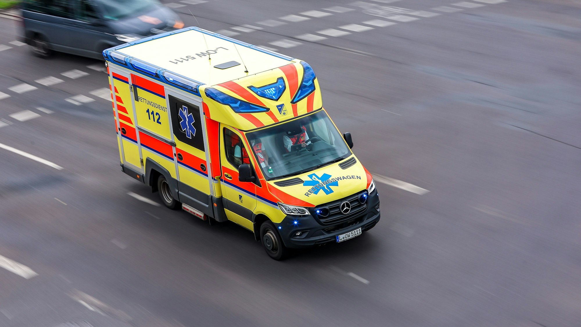 Ein Rettungswagen fährt mit Blaulicht über eine Straße.