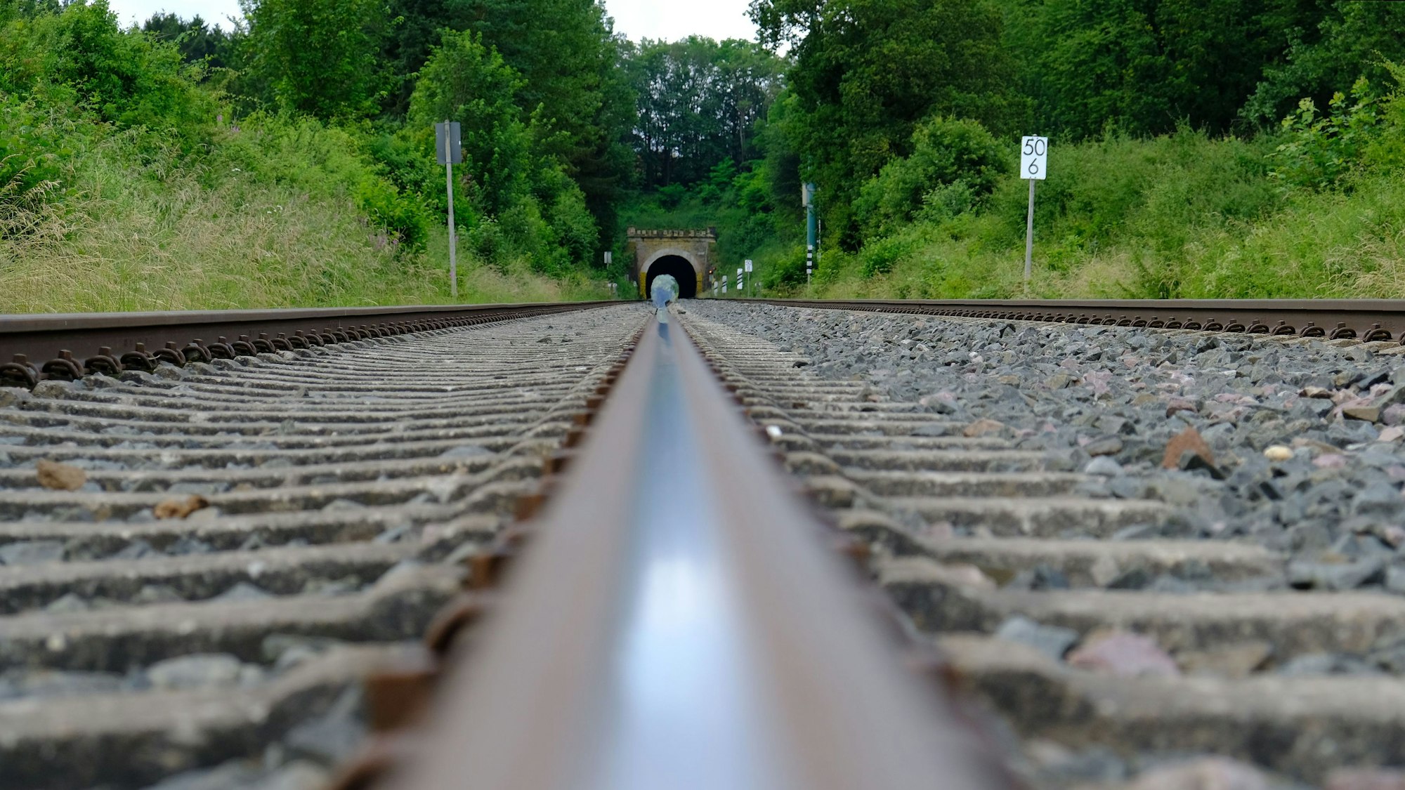 Schienen der Eifeltrasse in der Nähe von Kall. Im Hintergrund ist der Kaller Tunnel zu erkennen.