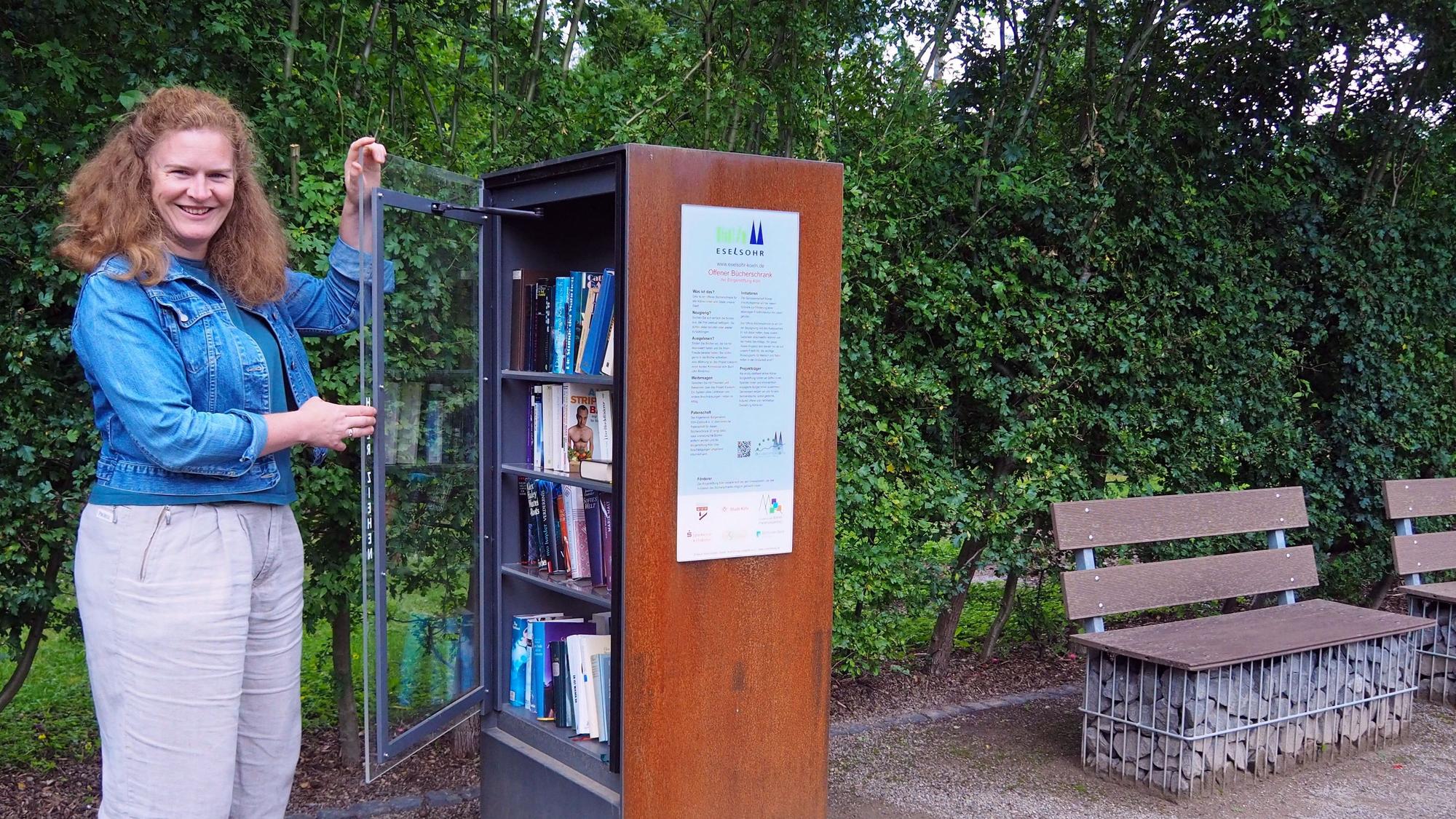 Josefa Raab öffnet die Glastür eines Bücherschranks