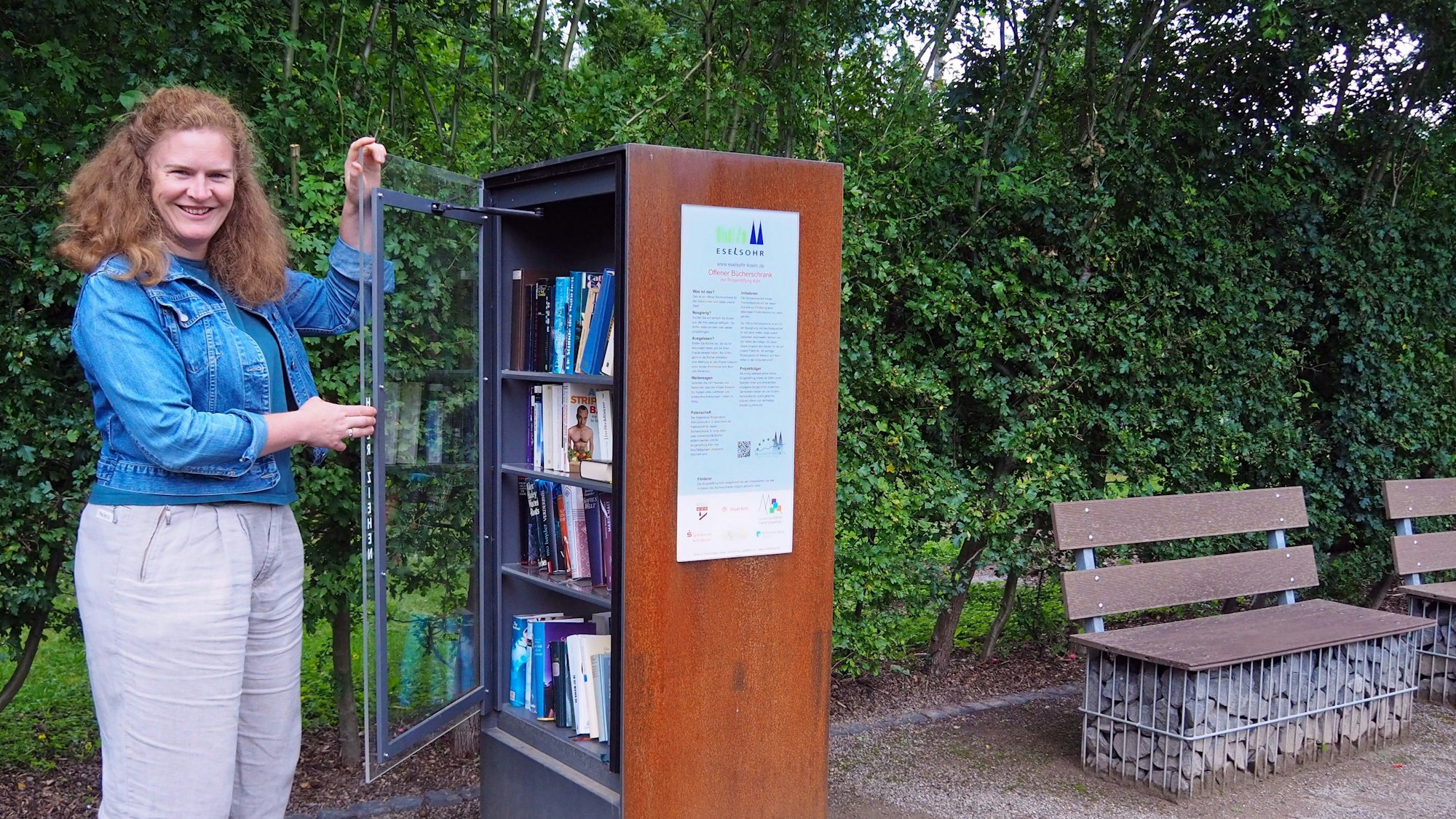 Josefa Raab öffnet die Glastür eines Bücherschranks