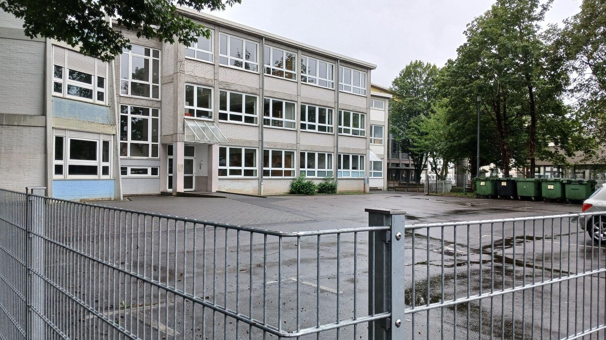 Ein Schulgebäude hinter einem Gitterzaun