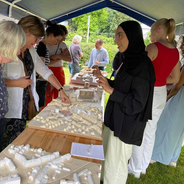 Frauen stehen um ein Architekturmodell auf einem Tisch