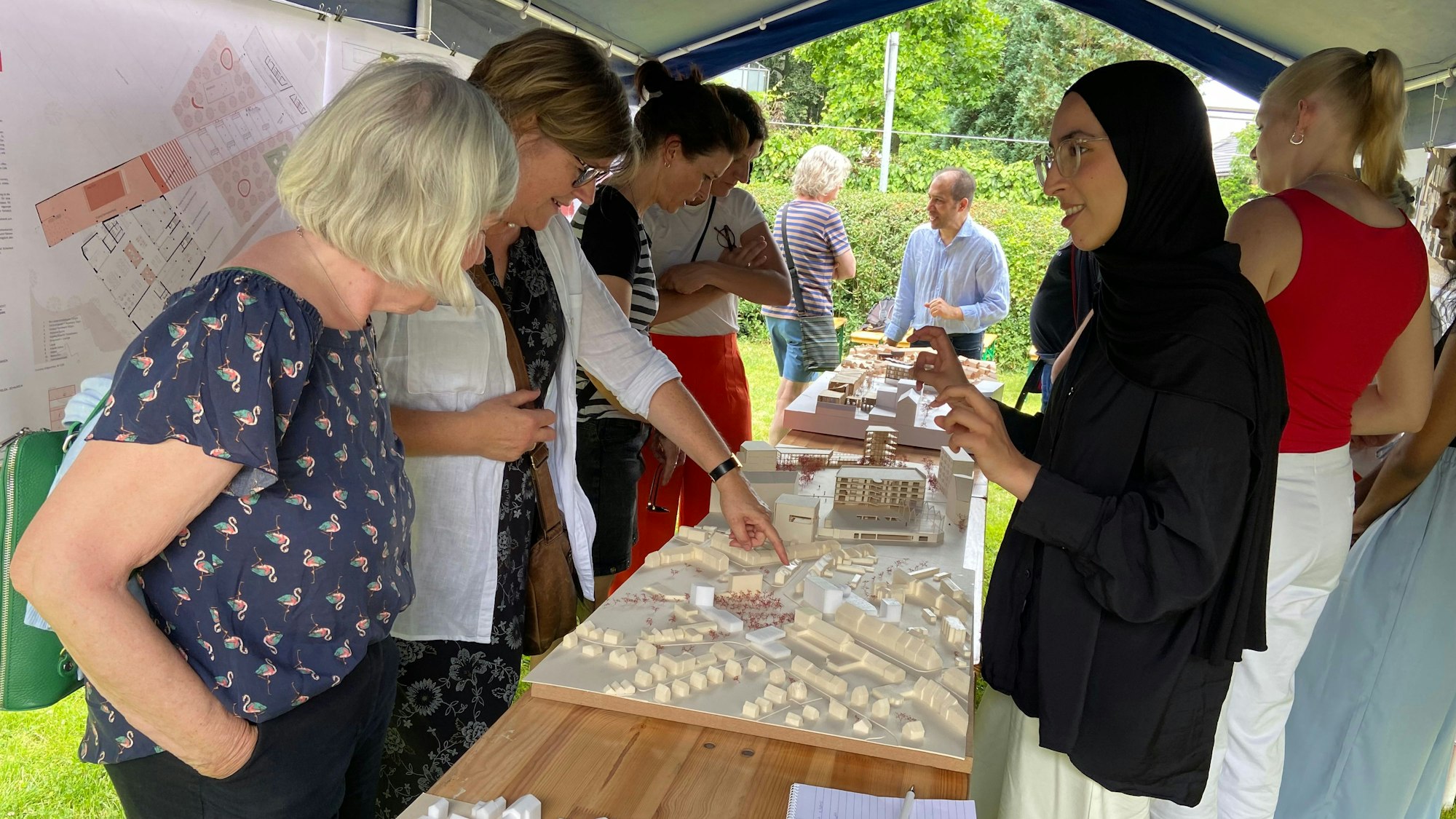 Frauen stehen um ein Architekturmodell auf einem Tisch