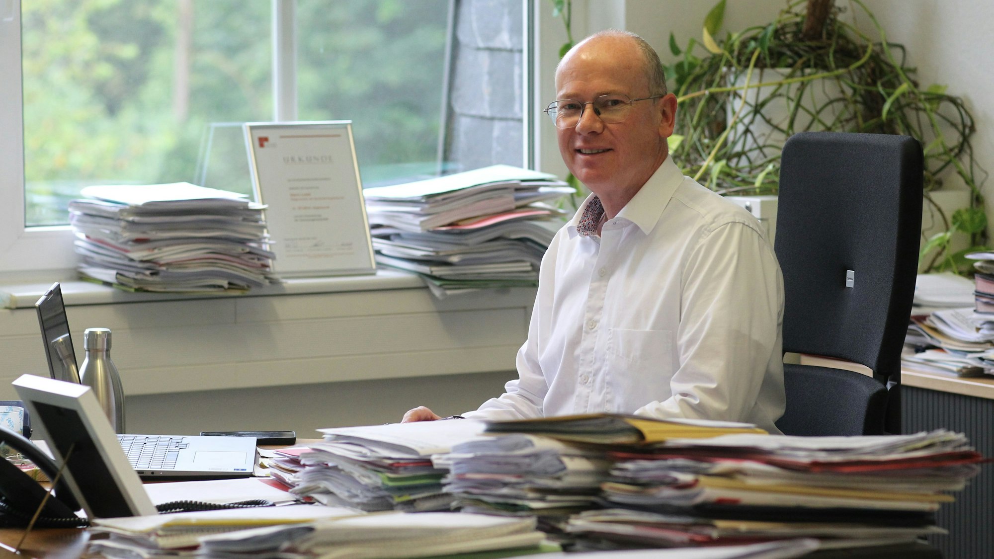 Ein Mann sitzt an einem Schreibtisch voller Akten