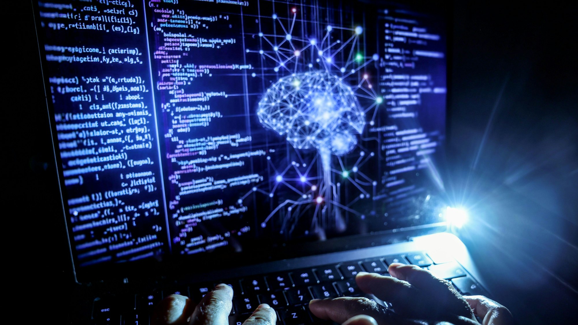 Nordrhein-Westfalen, Köln: Eine Person arbeitet am Rechner, auf dessen Bildschirm ein durch Künstliche Intelligenz generiertes Illustrationsbild mit Code verschiedener Programmiersprachen und einem neuronalen Netzwerk-Diagramm zu sehen ist. (Symbolbild)