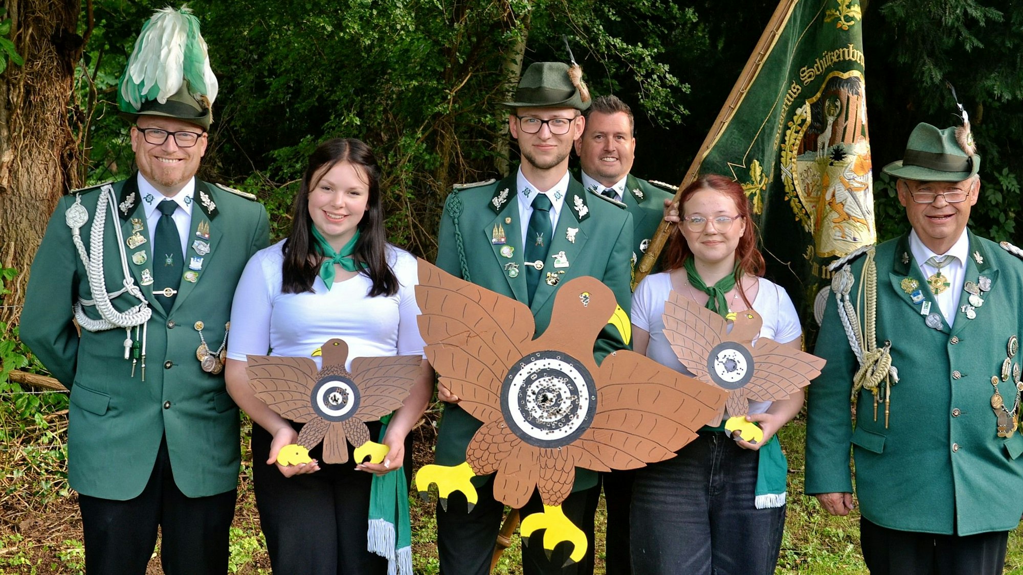 Die Nemmenicher Schützen psieren in Uniformen und halten Vögel und Fahne.