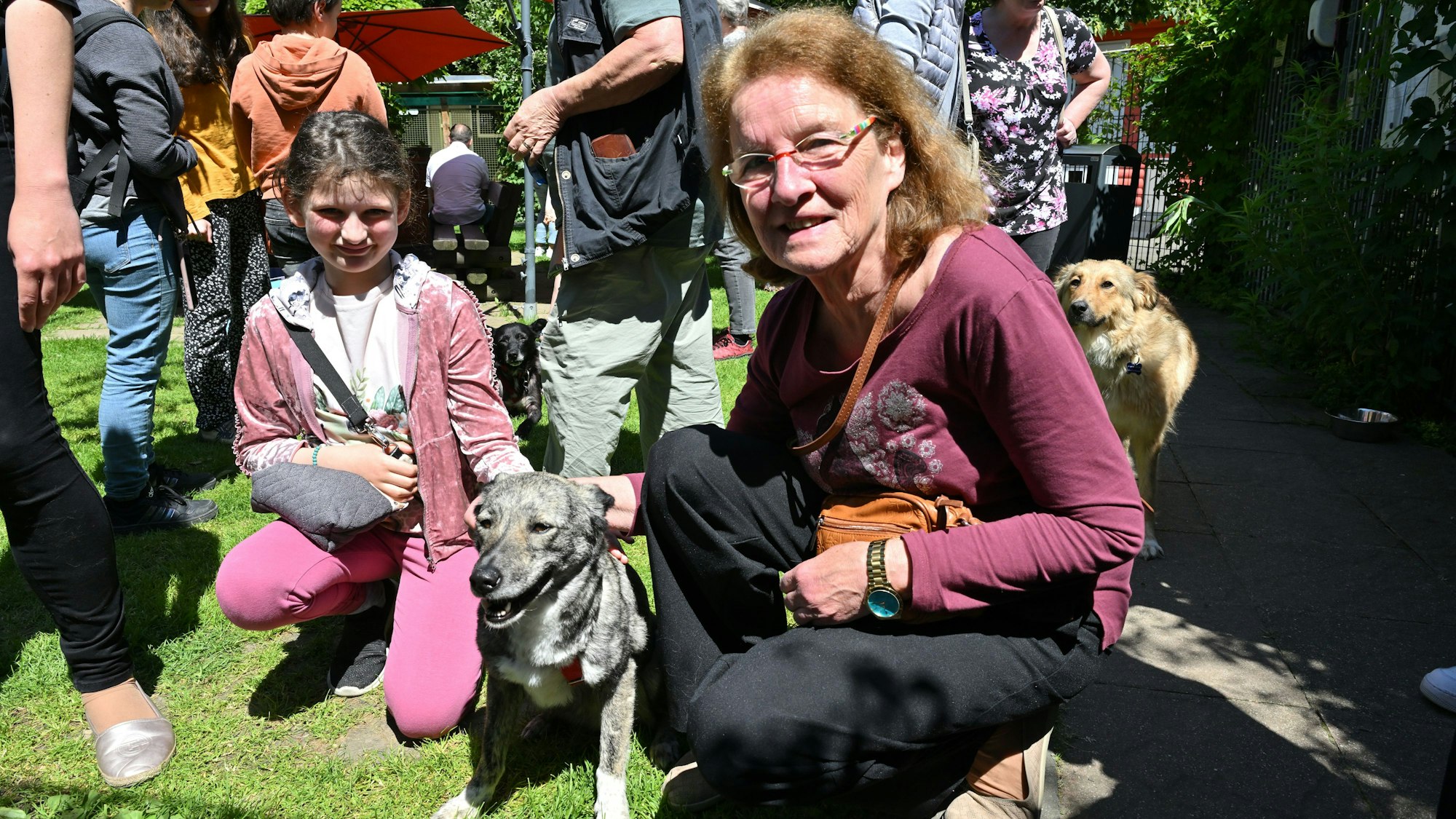 Eine Frau und ein Mädchen knien neben einem Hund.