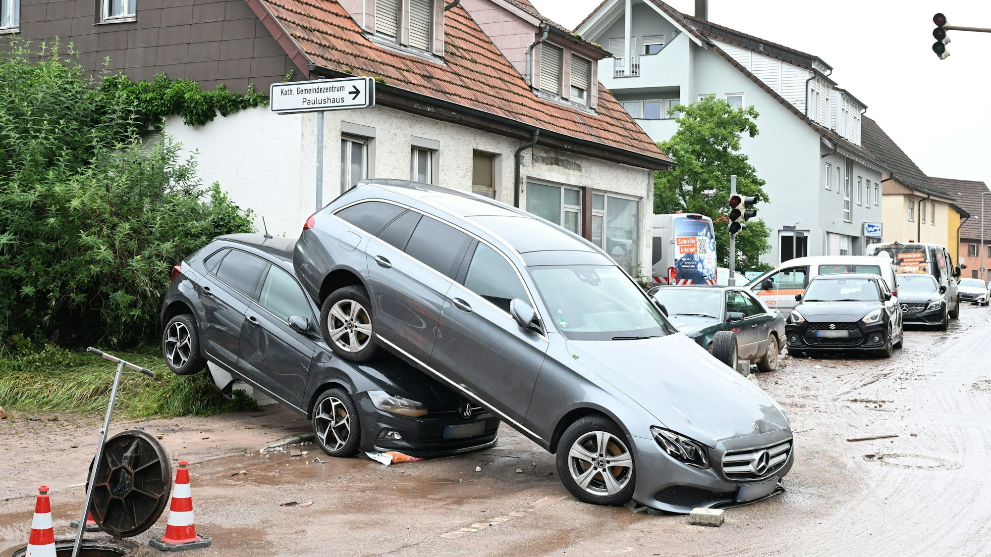 Auf einer Straße in Miedelsbach in Baden-Württemberg stehen Fahrzeuge, die durch ein Hochwasser nach einem Unwetter weggespült wurden.