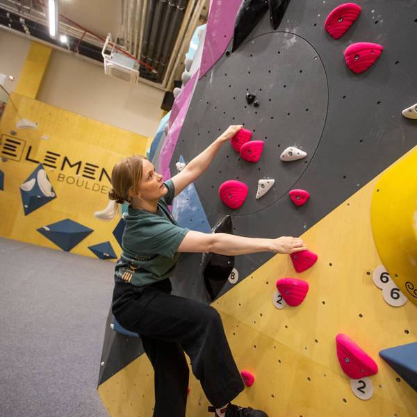 Eine Frau hängt an der Kletterwand
