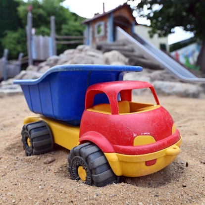 Ein Spielzeuglaster in einem Sandkasten auf einem Spielplatz.