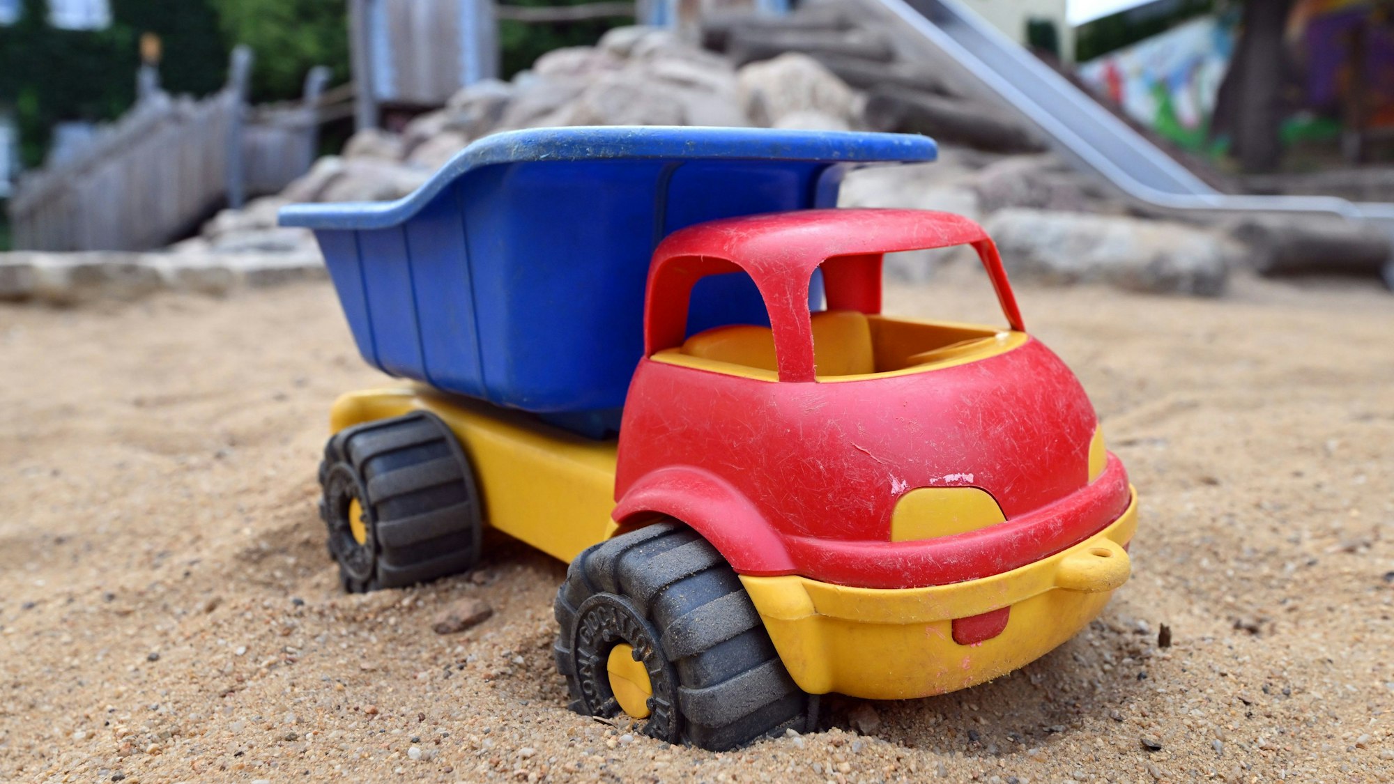 Ein Spielzeuglaster in einem Sandkasten auf einem Spielplatz.