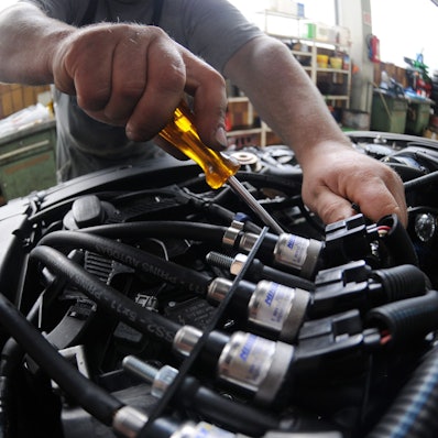 Ein Mechaniker arbeitet in einer Autowerkstatt im Motorraum eines Fahrzeugs mit Gasantrieb.
