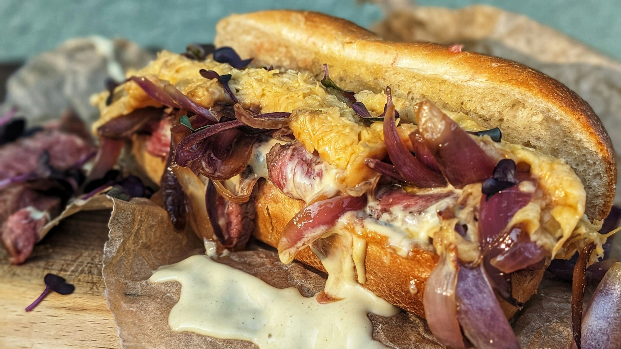 Ein Baguette-Brötchen ist gefüllt mit Fleisch, Zwiebeln und geschmolzenem Käse.