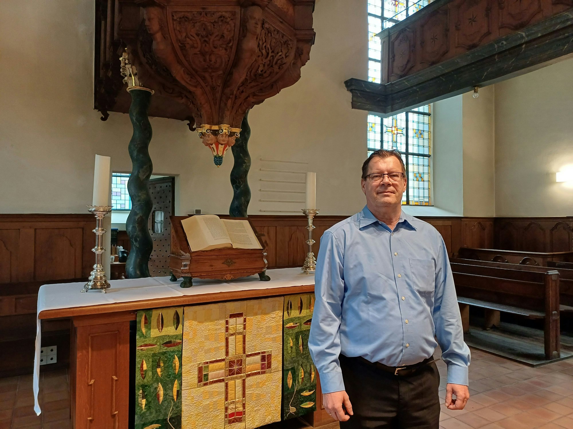 Ein Mann steht vor einem Altar in einer Kirche.
