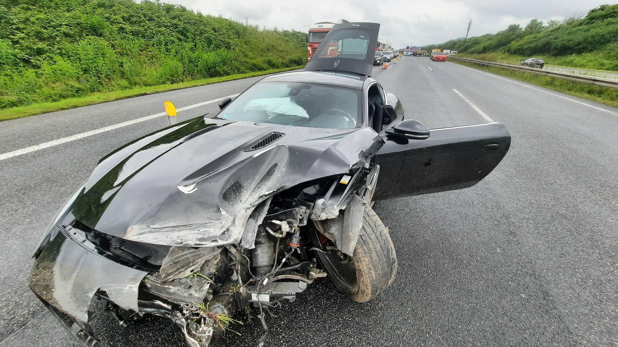Ein Sportwagen steht auf der Autobahn, die Front des Fahrzeugs ist erheblich beschädigt.