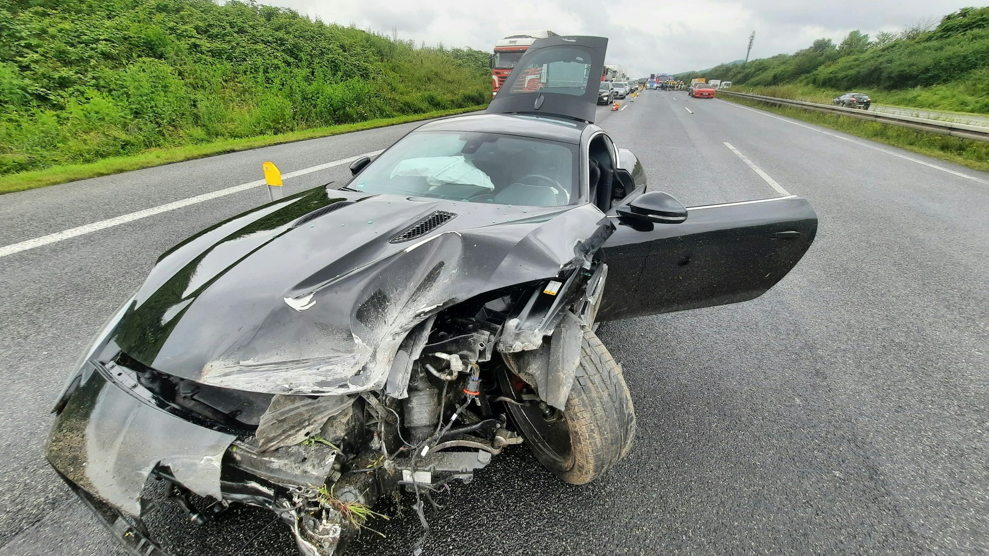 Ein Sportwagen steht auf der Autobahn, die Front des Fahrzeugs ist erheblich beschädigt.