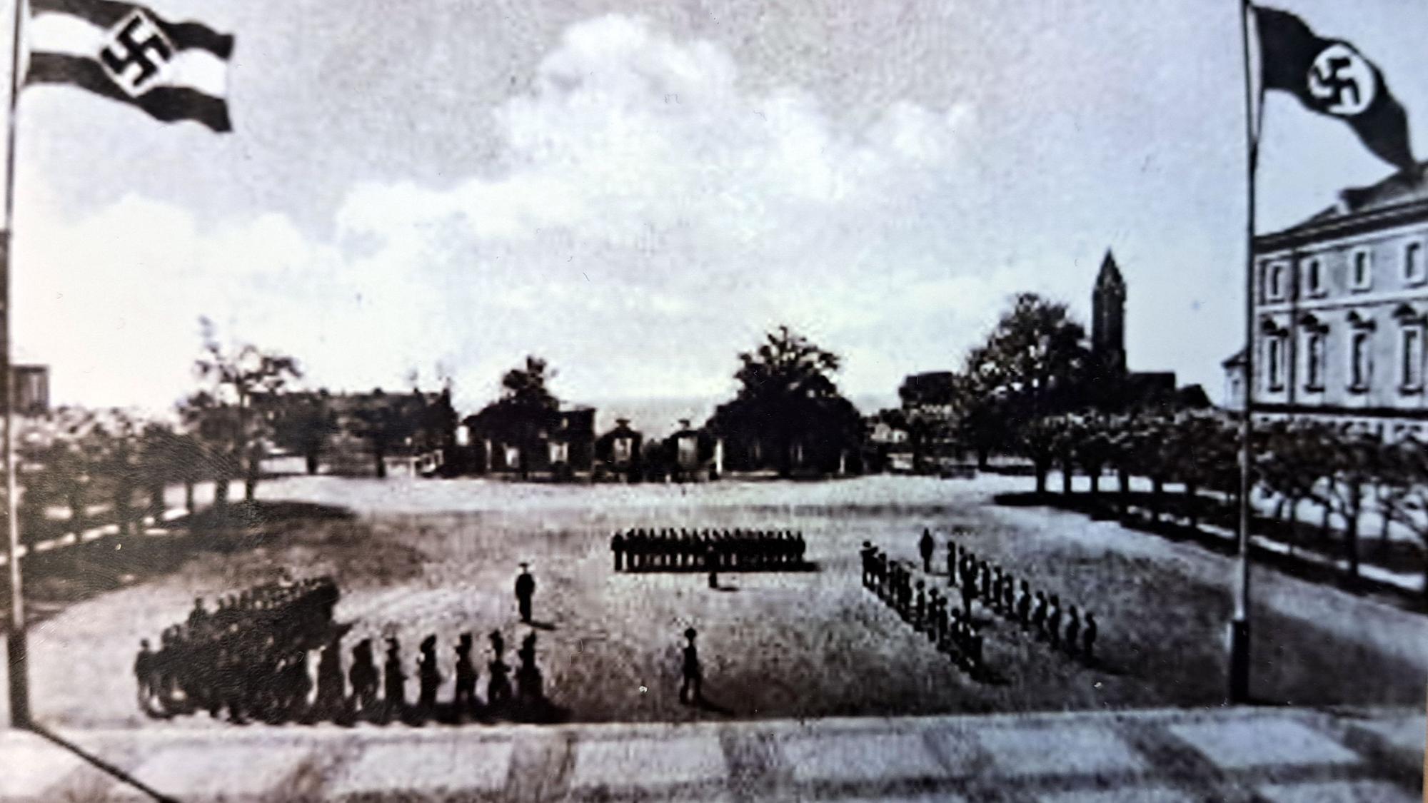 Auf dem historischen Foto vom Schlosshof marschieren Soldaten, rechts und links wehen Nazi-Flaggen.