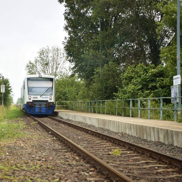 Ein Zug der Rurtalbahn fährt in Nemmenich am Bahnsteig ab.
