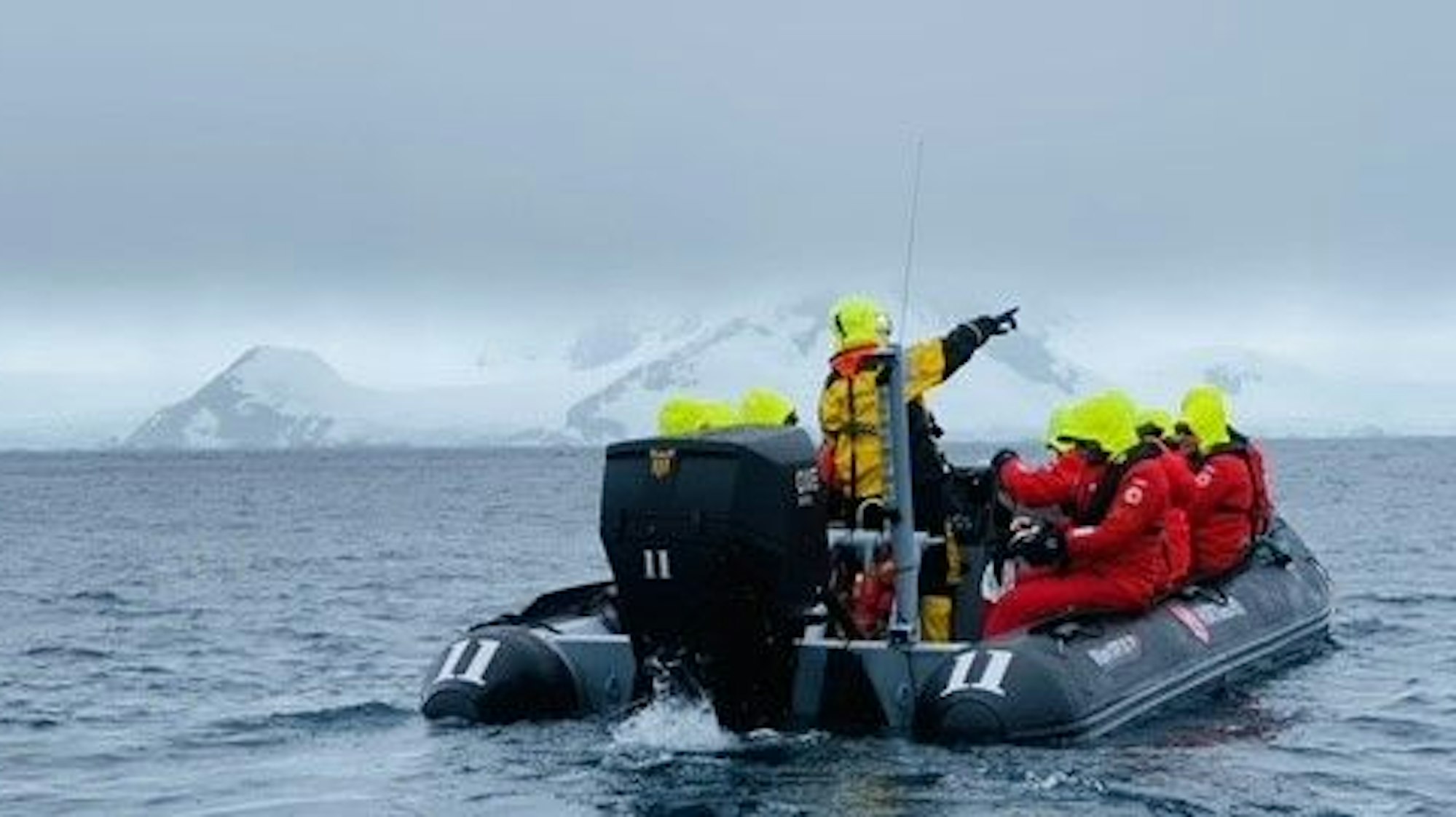 Menschen in roten Jacken sitzen in einem Zodiac-Schlauchboot.