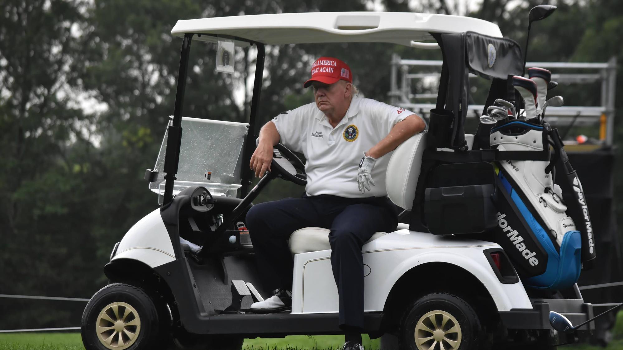 Donald Trump sitzt in einem Golfkart.