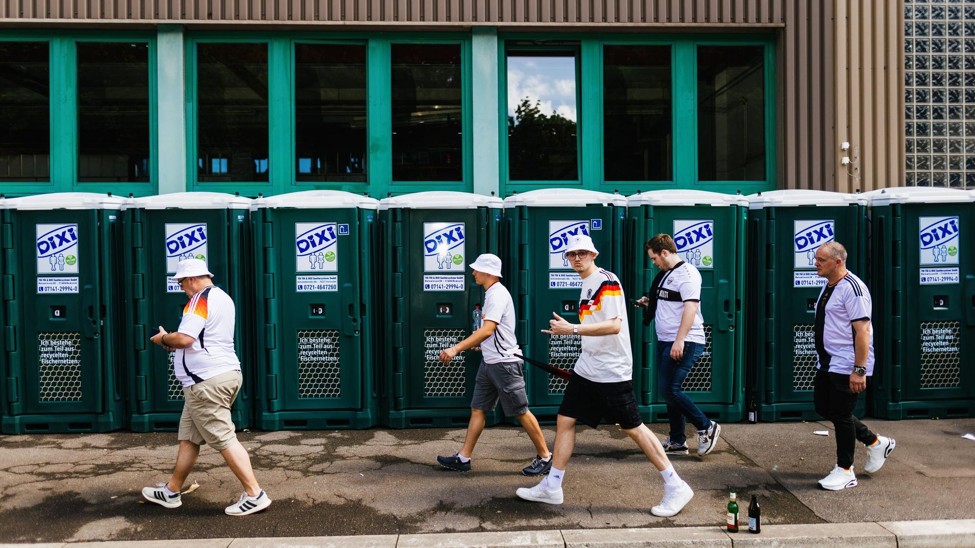 Deutsche Fans gehen beim Fanmarsch in der Innenstadt an mobilen Toiletten vorbei.
