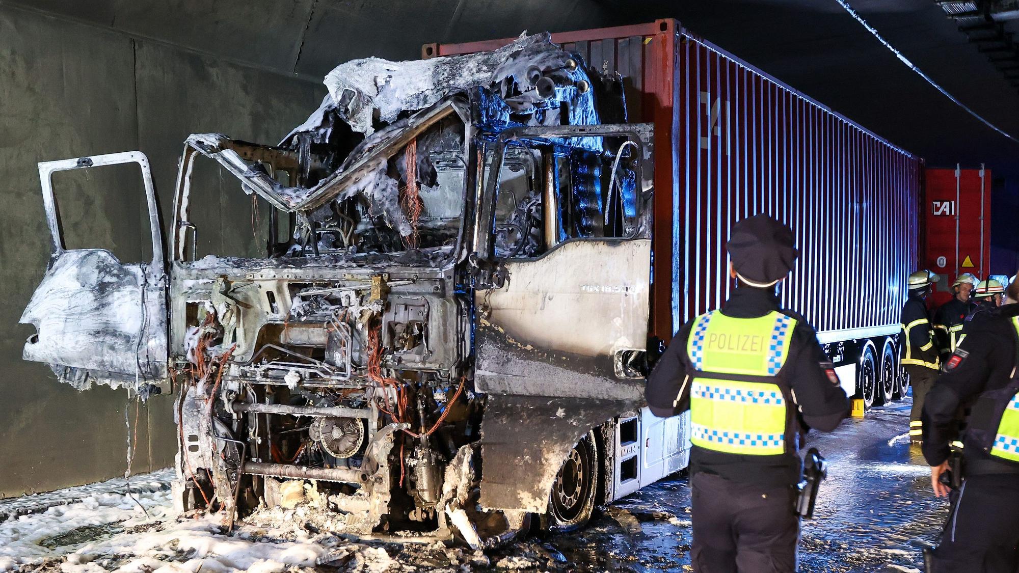 Einsatzkräfte stehen im Elbtunnel an einer ausgebrannten Lkw-Zugmaschine.