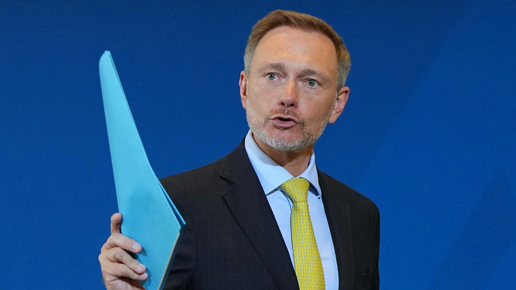 Christian Lindner (FDP), Bundesminister der Finanzen, winkt mit einem blauen Hefter. (Archivbild)