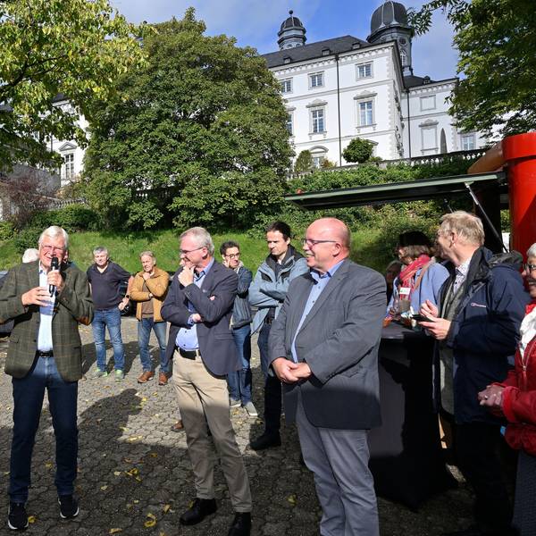 Viele Menschen stehen unterhalb der Türme eines Barockschlosses.