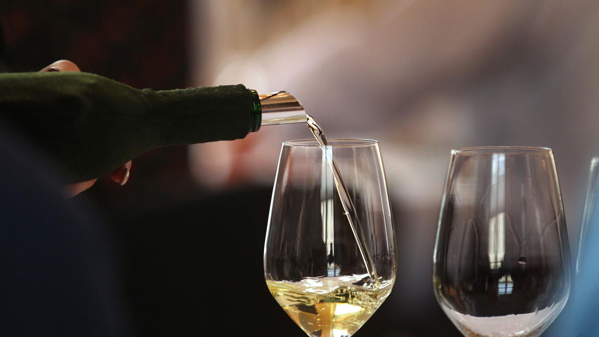 Ein Glas wird mit Weißwein gefüllt. (Symbolbild)