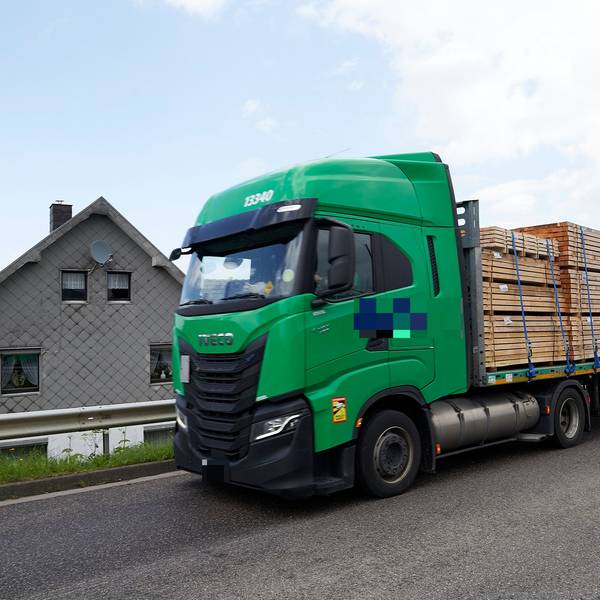 Ein Lkw fährt an einem Haus vorbei.