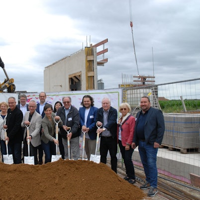 Männer und Frauen setzen einen Spatenstich.