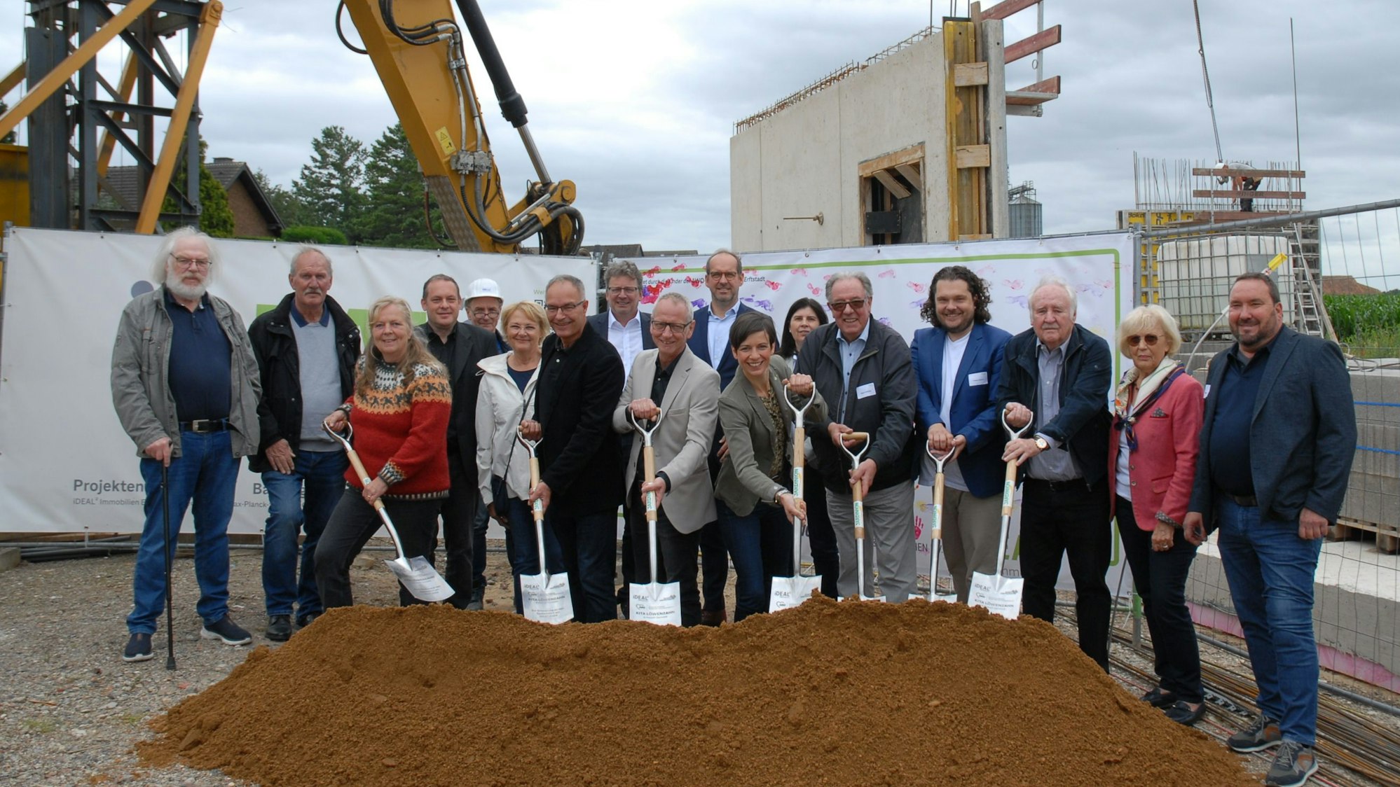 Männer und Frauen setzen einen Spatenstich.