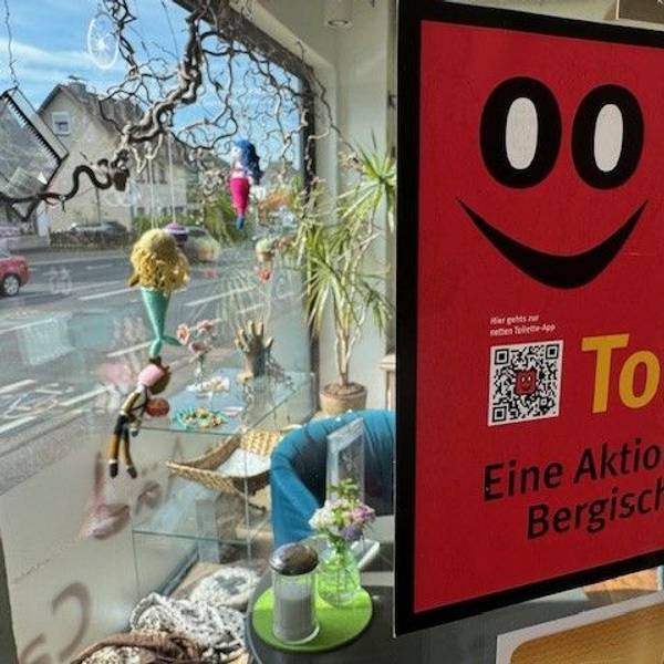 Zu sehen ist das rote Logo der Netten Toilette, das in einem Schaufenster steht.