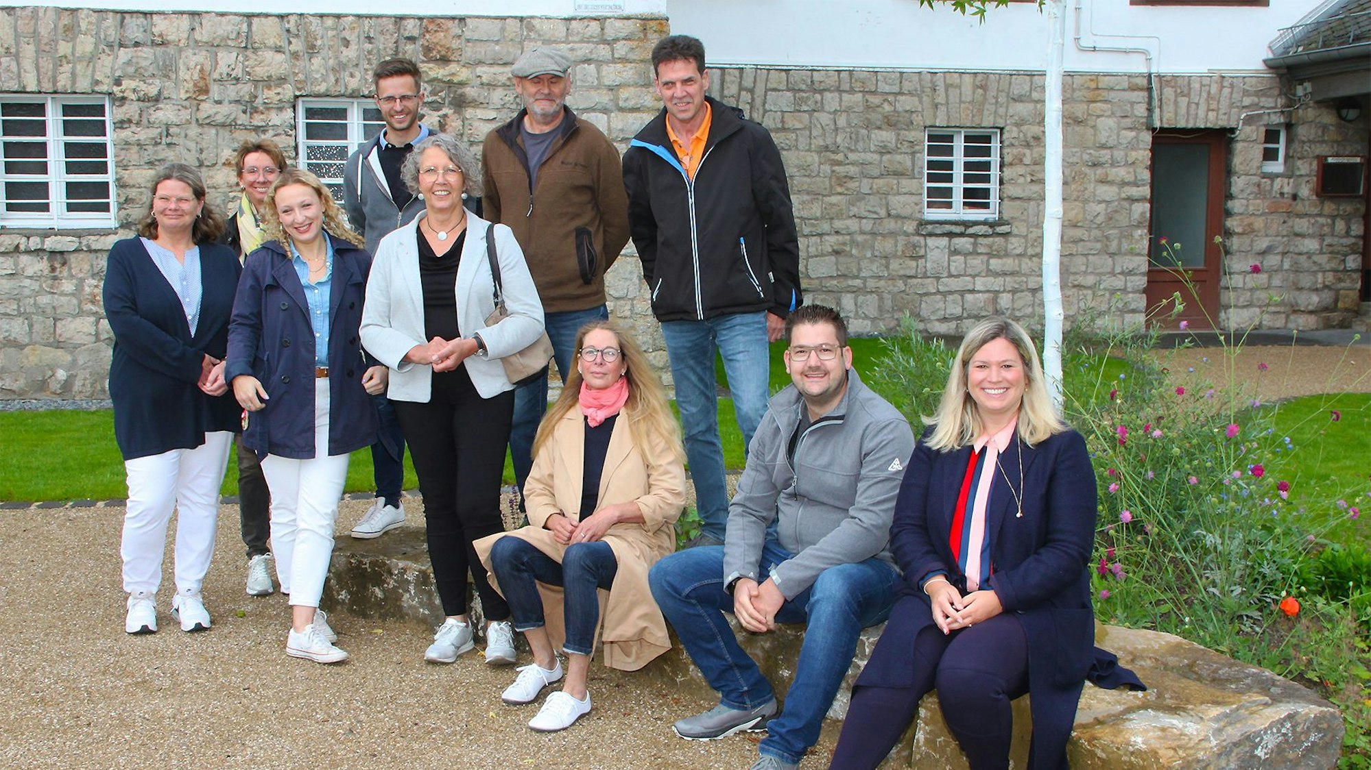 Auf den steinernen Bänken sitzen drei Leute, sieben weitere stehen.