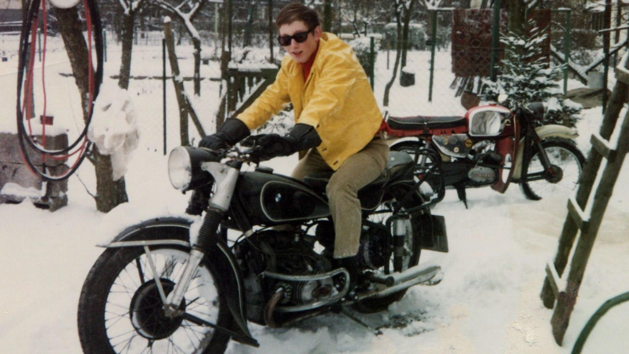 Ein junger Mann sitzt auf einem historischen Motorrad.