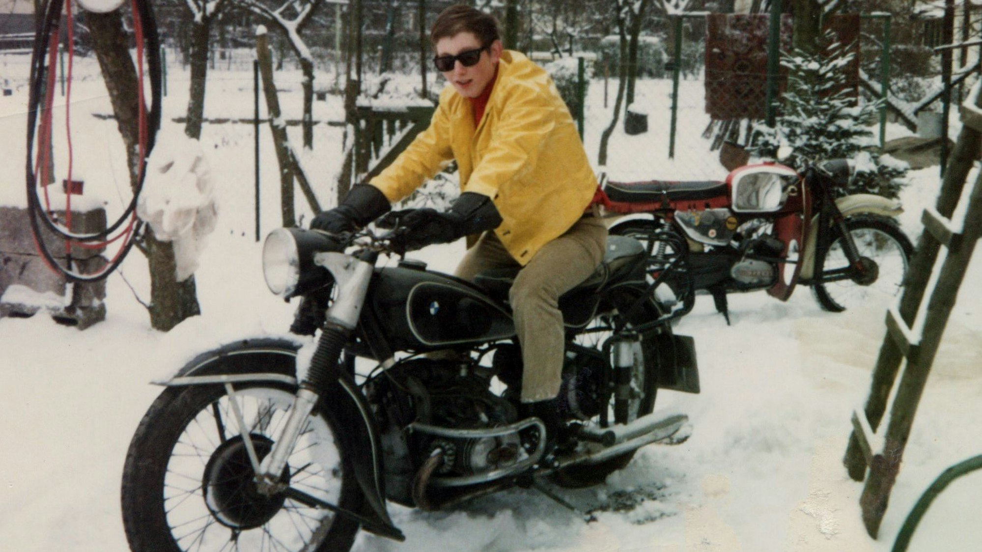 Ein junger Mann sitzt auf einem historischen Motorrad.