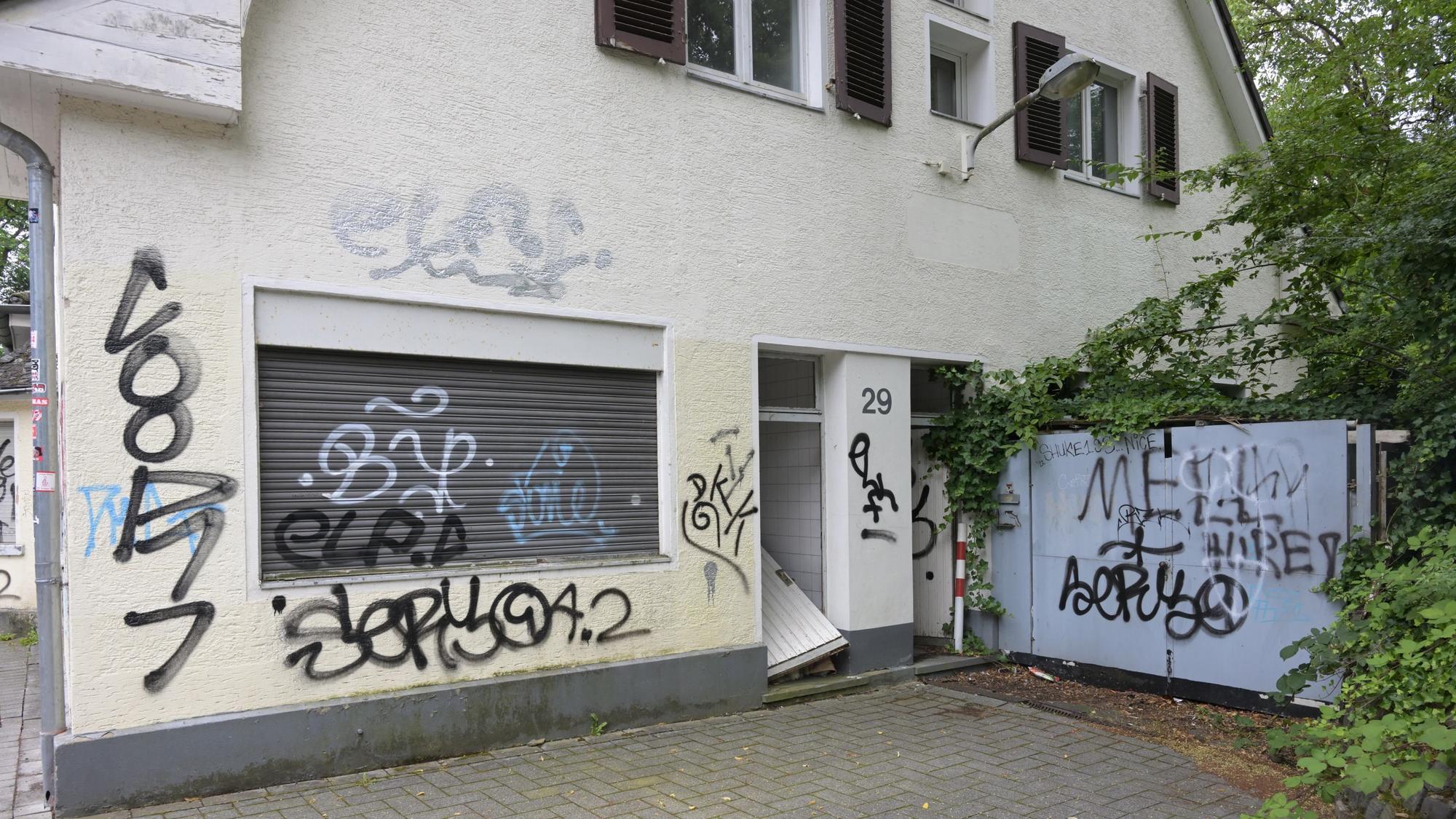Zu sehen ist die beschmierte Fassade des Gebäudes und die eingetretene Tür.