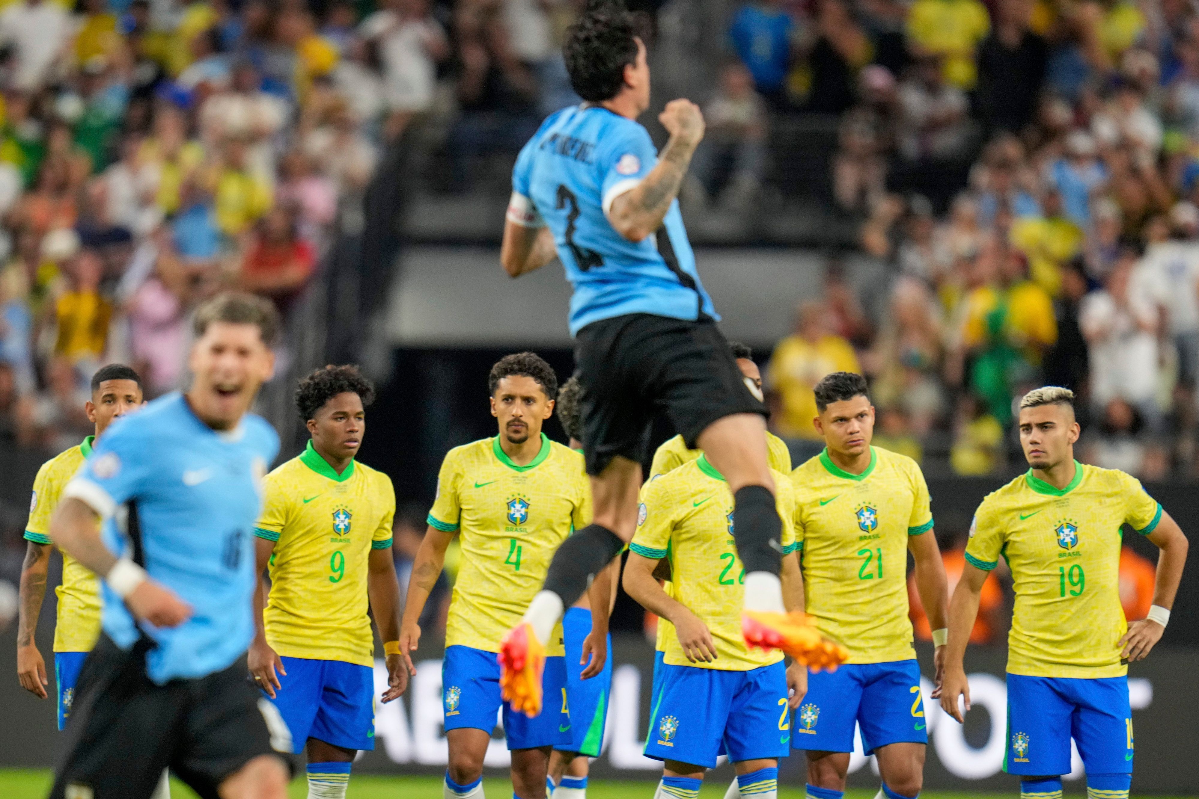Brasilianische Spieler stehen im Mittelfeld, während uruguayische Spieler ihren Sieg im Elfmeterschießen während des Viertelfinales der Copa America feiern.