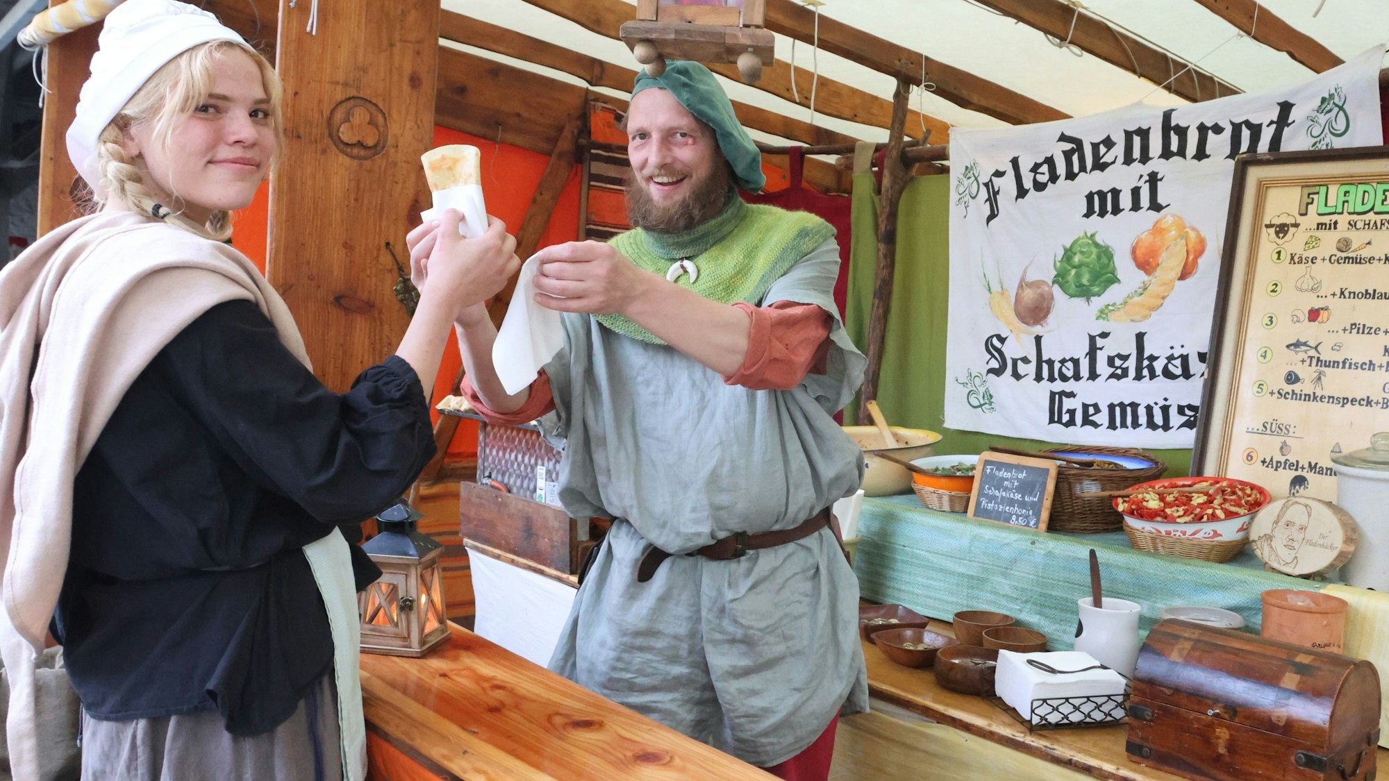 Mittelaltermarkt Denklingen, Kundin Merle kauft ein gefülltes Fladenbrot bei Martin Edelmann.