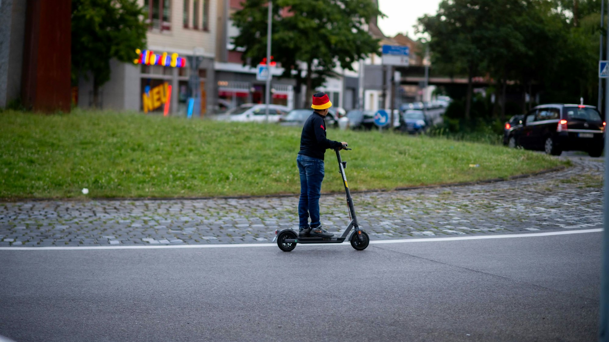 Das Bild zeigt einen Jungen, der mit einem E-Roller durch den Kreisverkehr fährt.