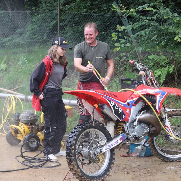 Ein Mann und seine Tochter waschen eine Motocross-Maschine.