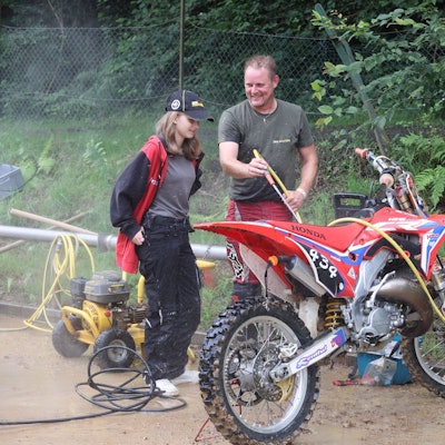 Ein Mann und seine Tochter waschen eine Motocross-Maschine.