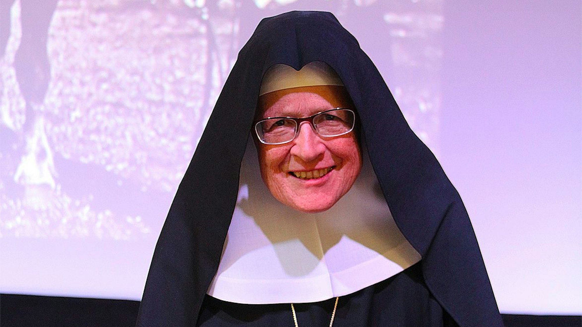 Christiana Reemts hält einen Vortrag und steht vor einer Projektion an der Wand.