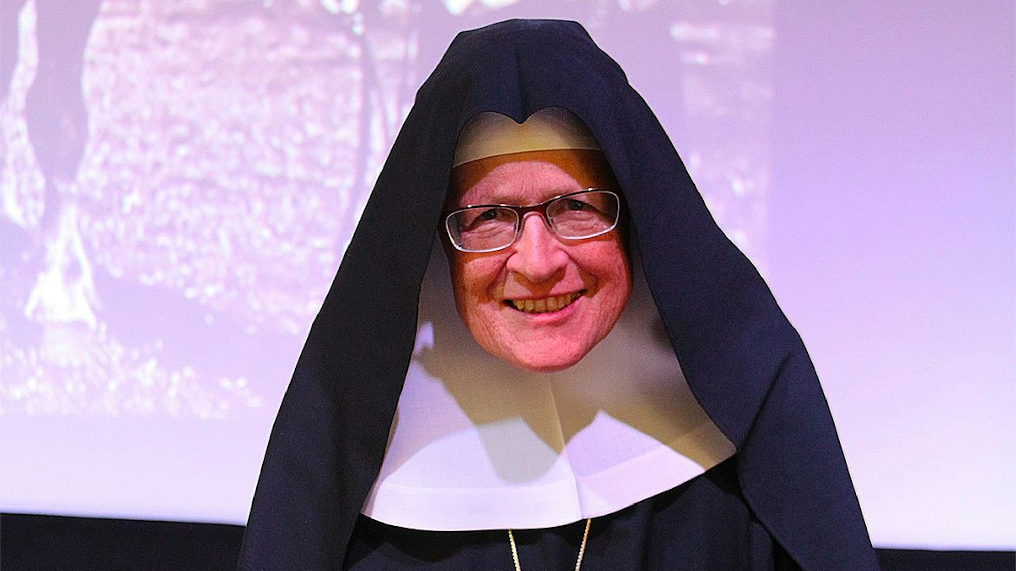 Christiana Reemts hält einen Vortrag und steht vor einer Projektion an der Wand.