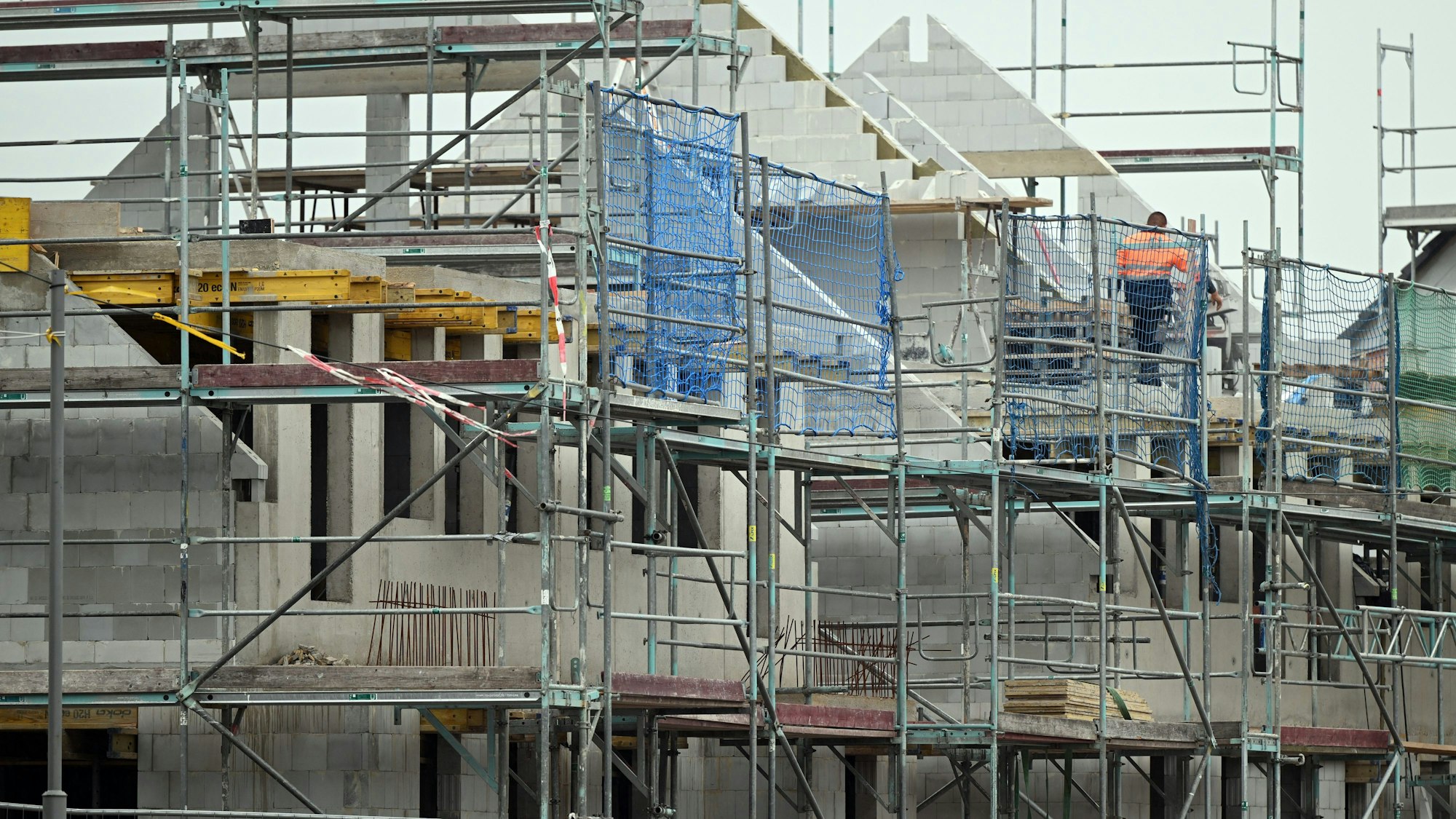 ARCHIV - 20.10.2022, Nordrhein-Westfalen, Duisburg: Gerüste stehen an noch nicht fertig gebauten Häusern in einem Neubaugebiet. Die Nachfrage nach Baufinanzierungen ist im Zuge gestiegener Zinsen erneut eingebrochen. (zu dpa «Studie: Neugeschäft mit Baufinanzierungen bricht erneut ein») Foto: Federico Gambarini/dpa +++ dpa-Bildfunk +++