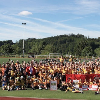 Viele Kinder, Jugendliche und Erwachsene haben sich zum Gruppenbild auf dem Sportplatz versammelt.
