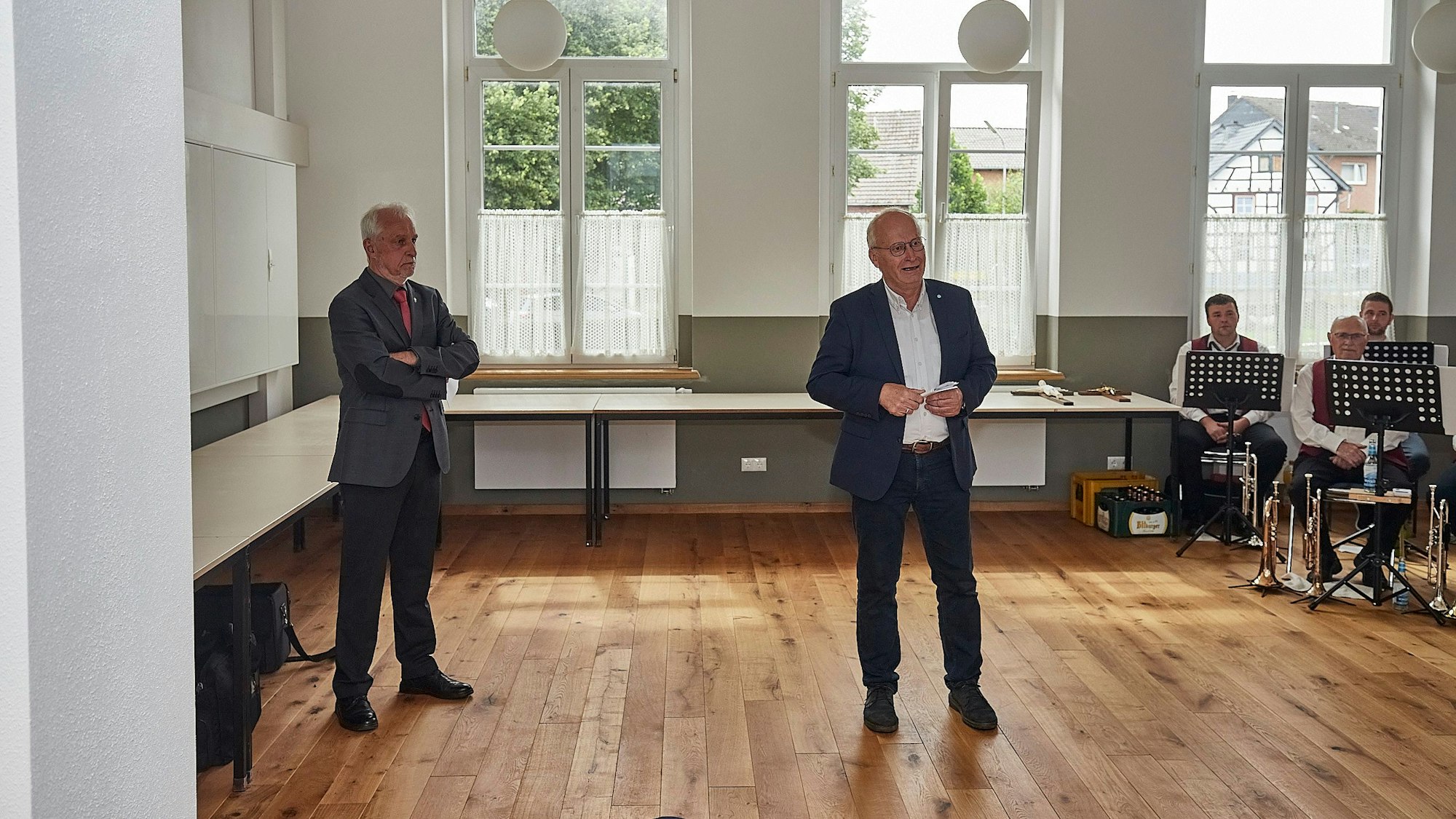 Klaus-Peter Hoß und Bürgermeister Dr. Hans-Peter Schick stehen auf dem Holzfußboden des neuen Dorfgemeinschaftshauses