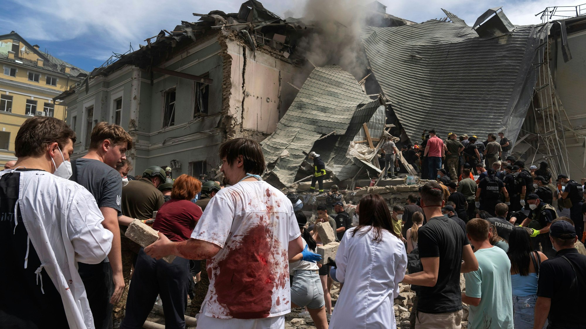 Kiew: Rettungskräfte, Freiwillige und medizinisches Personal, einige in blutverschmierten Uniformen, räumen die Trümmer auf und suchen nach Opfern, nachdem eine russische Rakete das Okhmatdyt-Kinderkrankenhaus getroffen hat